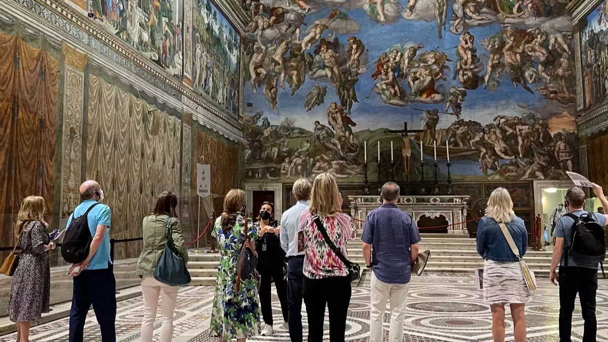 Visitors listen to a guide and look at Michelangelo’s frescoes inside the Sistine Chapel