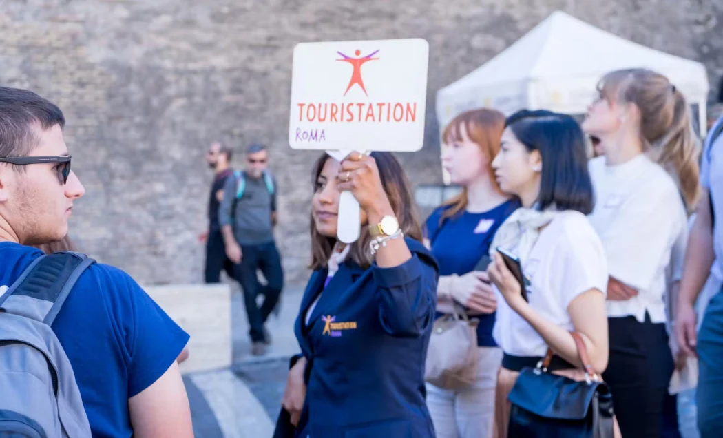 Tour guide holds a Touristation sign while a group gathers near the Vatican Museums entrance